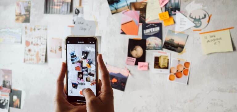 Blicke auf Smartphonedisplay vor einer Wand mit Post-Its